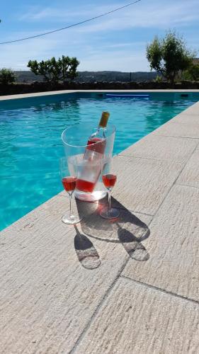 two glasses of wine sitting on a table next to a pool at Casinha CB in Casteição