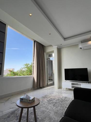 a living room with a tv and a large window at فيلا اورنيلا in Al Hada