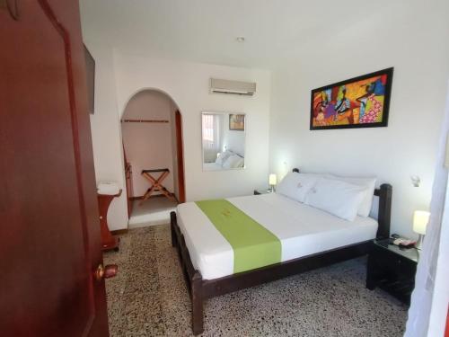 a bedroom with a white bed with a green blanket at Hotel Villa Ricaurte in Girardot