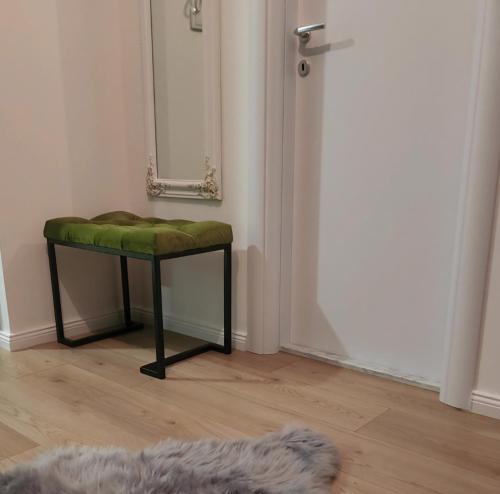 un tabouret avec un siège vert dans une pièce avec un miroir dans l'établissement Apartman MK, à Lukavica