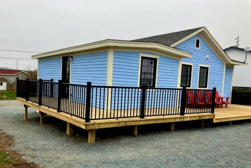 a blue house with a large wooden deck at Rural Town Oasis in Bonavista