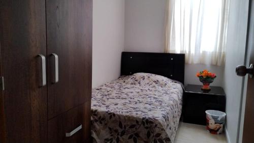 1 dormitorio pequeño con 1 cama y armario de madera en Alojamiento en Cúcuta al lado del Centro Comercial Jardín Plaza en Cúcuta