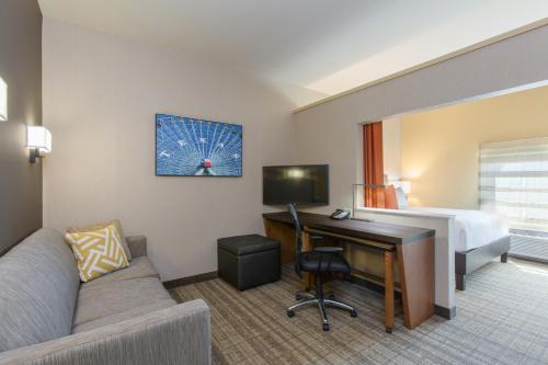a hotel room with a bed and a desk with a computer at Cambria Hotel Plano - Frisco in Plano