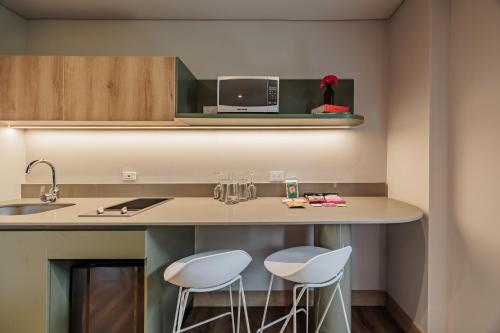 a kitchen with two stools at a counter with a microwave at The Somos Central Hotel Poblado in Medellín