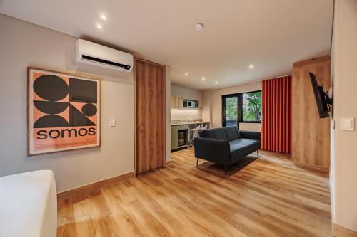 a living room with a black chair and a kitchen at The Somos Central Hotel Poblado in Medellín
