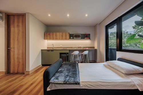 a bedroom with a large bed and a kitchen at The Somos Central Hotel Poblado in Medellín