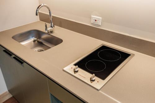 a kitchen with a sink and a stove at The Somos Central Hotel Poblado in Medellín