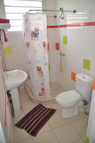 a bathroom with a toilet and a shower curtain at Ô PARADIS TERRESTRE in Capesterre