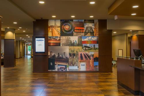 a lobby of a hotel with a large wall of posters at Cambria Hotel Plano - Frisco in Plano
