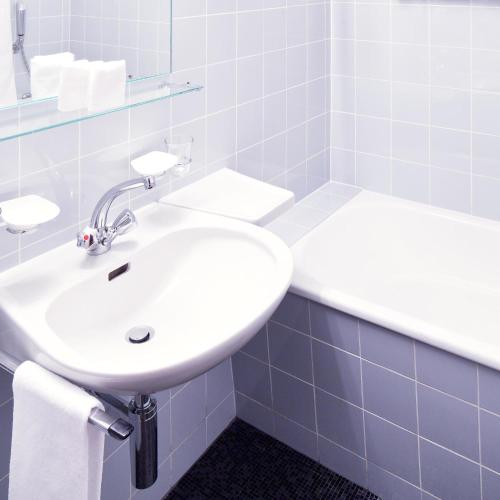 a white sink in a bathroom with blue tiles at Schnider Bed&Breakfast und Café in Vals