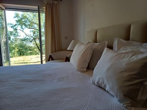 a bedroom with a bed with white pillows and a window at Fátima-Ourém - Quinta da Luz - breakfast included in Ourém
