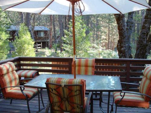 a table and chairs with an umbrella on a deck at Wawona Home in Wawona
