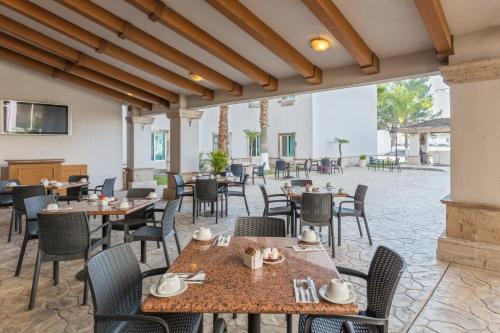 voco Saltillo Suites, an IHG Hotel في سالتيلو: مطعم بطاولات وكراسي وفناء
