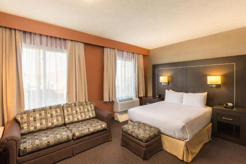 a hotel room with a bed and a couch at voco Saltillo Suites, an IHG Hotel in Saltillo