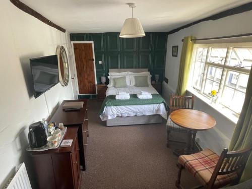 a bedroom with a bed and a table and a desk at The Swan Inn in Monks Eleigh
