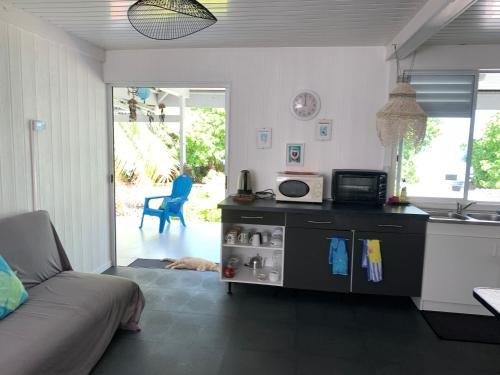 a kitchen and living room with a couch and a microwave at LE FARE BLEU Tiputa Rangiroa in Tiputa
