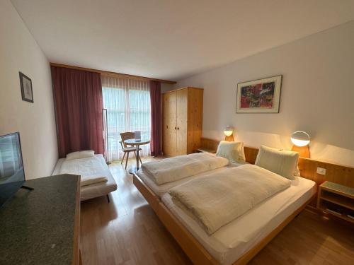 ein Schlafzimmer mit einem großen Bett und einem Tisch in der Unterkunft Hotel Schöntal in Filisur