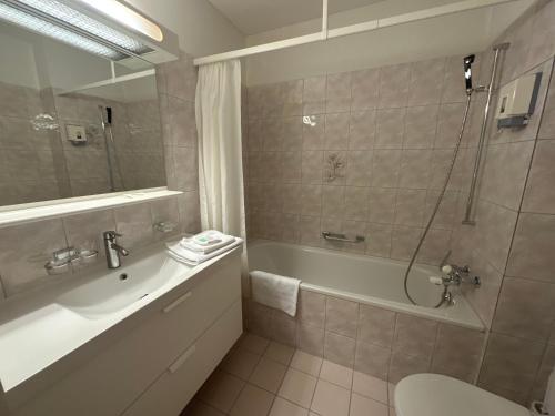 een badkamer met een bad, een wastafel en een douche bij Hotel Schöntal in Filisur