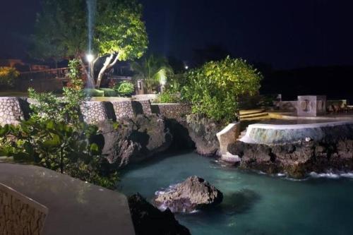 a bridge over a river in a yard at night at Villa Gilgal in Kings Pen