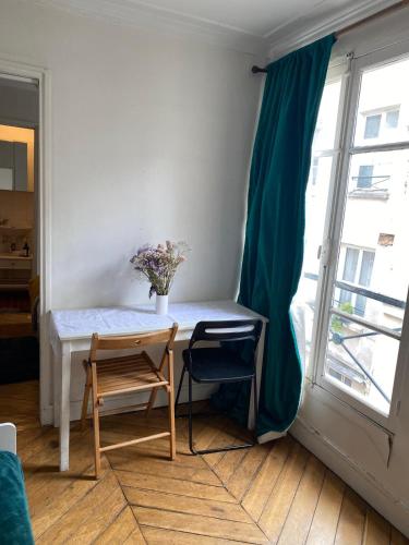 une table et deux chaises dans une pièce avec une fenêtre dans l'établissement Appartement bien placé, à Paris