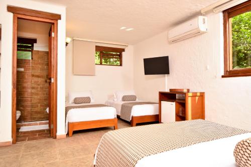 a hotel room with two beds and a television at La Campana Hotel Boutique in Medellín