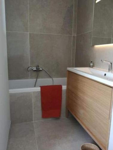 La salle de bains est pourvue d'une baignoire, d'un lavabo et d'une serviette rouge. dans l'établissement Villa de charme avec piscine en plein cœur du Var, à Rocbaron