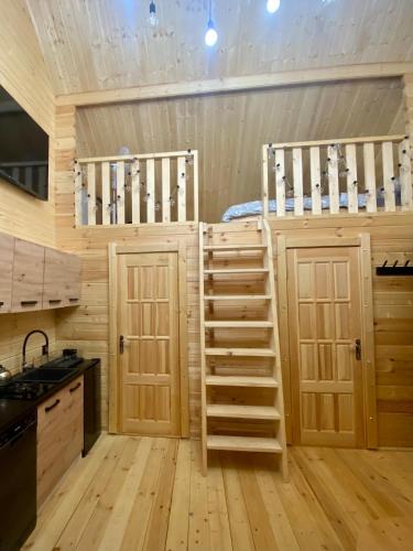 a cabin kitchen with a bunk bed and wooden floors at DOMEK W BRZOZACH nad jeziorem z balią na wyłączność in Lgiń