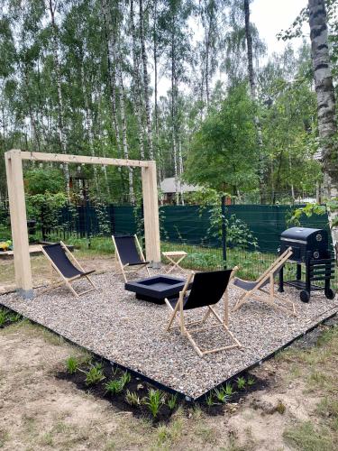a group of chairs and a grill in a yard at DOMEK W BRZOZACH nad jeziorem z balią na wyłączność in Lgiń