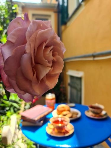 a pink rose sitting on a blue table with plates of food at Il sogno del capitano in Pieve Ligure
