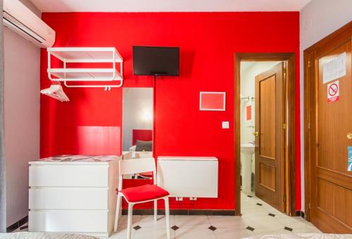 Habitación roja con pared roja y silla roja en Hostal Tropical en Almuñécar