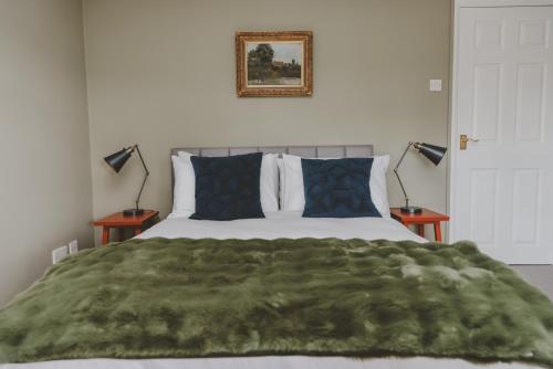 a bedroom with a green blanket on a bed with two lamps at The Butterleigh Inn in Cullompton
