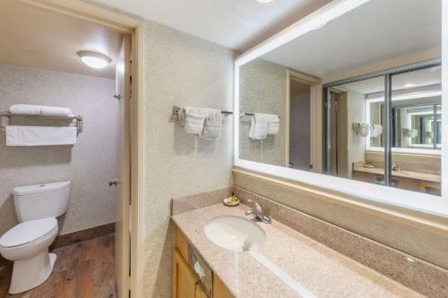 a bathroom with a toilet and a sink and a mirror at Best Western Plus Hill House in Bakersfield