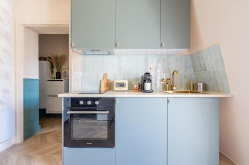 une cuisine avec des armoires blanches et un four noir dans l'établissement Studio Luxe Paris, à Paris