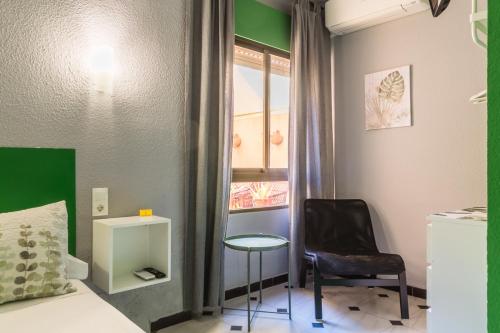 a room with a bed and a chair and a window at Hostal Tropical in Almuñécar