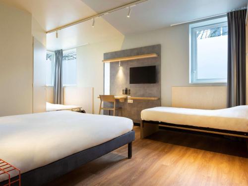 um quarto de hotel com duas camas e uma secretária em ibis budget Antony Massy rénové 2024 em Antony