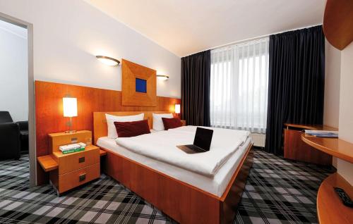 a hotel room with a bed with a laptop on it at Median Hotel Hannover Lehrte in Lehrte
