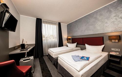 a hotel room with two beds and a television at Median Hotel Hannover Lehrte in Lehrte