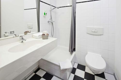 a white bathroom with a sink and a toilet at Median Hotel Hannover Lehrte in Lehrte