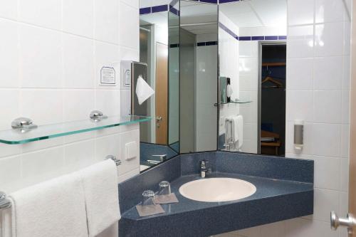 La salle de bains est pourvue d'un lavabo et d'un miroir. dans l'établissement Median Hotel Hannover Messe, à Hanovre