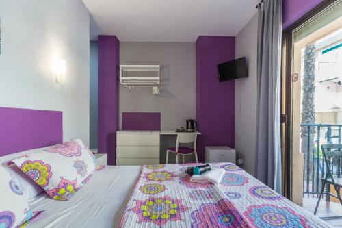 a bedroom with purple walls and a bed at Hostal Tropical in Almuñécar