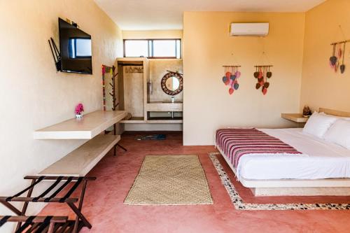 een slaapkamer met een bed, een bureau en een televisie bij Atenea Holbox in Holbox Island