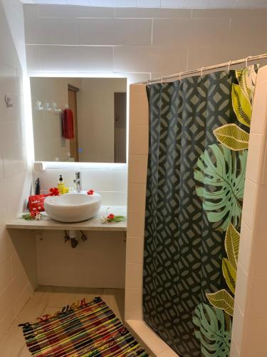 een badkamer met een wastafel en een spiegel bij A TOMO MAI Homestay in Faaa