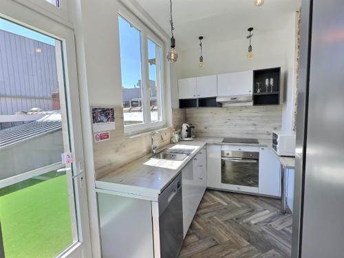 une cuisine avec des placards blancs et une grande fenêtre dans l'établissement Hypercentre Grand T4 équipé - Proximité Puy Du Fou, à Cholet