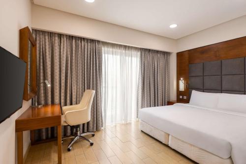 um quarto de hotel com uma cama, uma secretária e um computador em Levatio Suites Muscat, a member of Radisson Individuals em Mascate