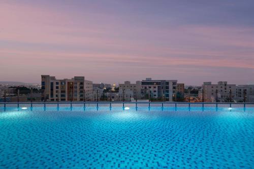 a large swimming pool with a city in the background at Levatio Suites Muscat, a member of Radisson Individuals in Muscat