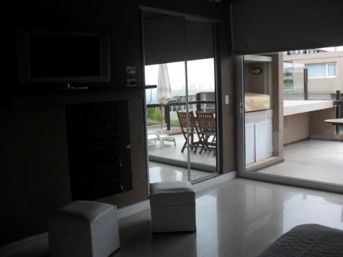 a living room with a television and a view of a patio at Linda Bay Spa de Mar in Mar de las Pampas