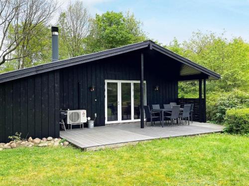 a black shed with a table and chairs on a deck at 6 person holiday home in Toftlund-By Traum in Vestergård