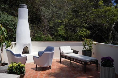 a patio with chairs and a bench and a fireplace at El Caminante Bar & Bungalows in Dana Point