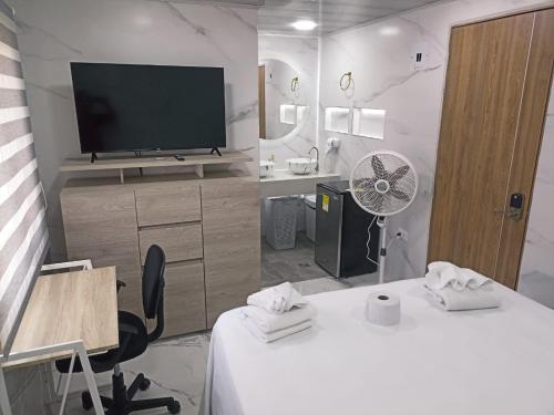 a living room with a tv and a desk with a desk at Hotel Orduz Centro Histórico de Cali in Cali