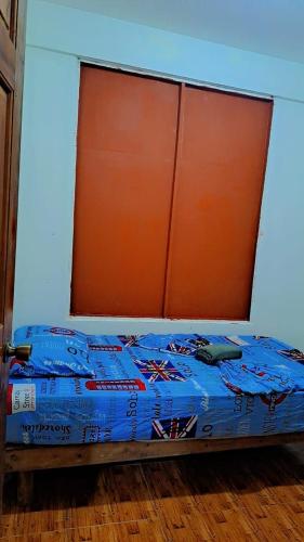 a bed with an orange headboard and blue sheets at Hostel Hook and Cook in Drake